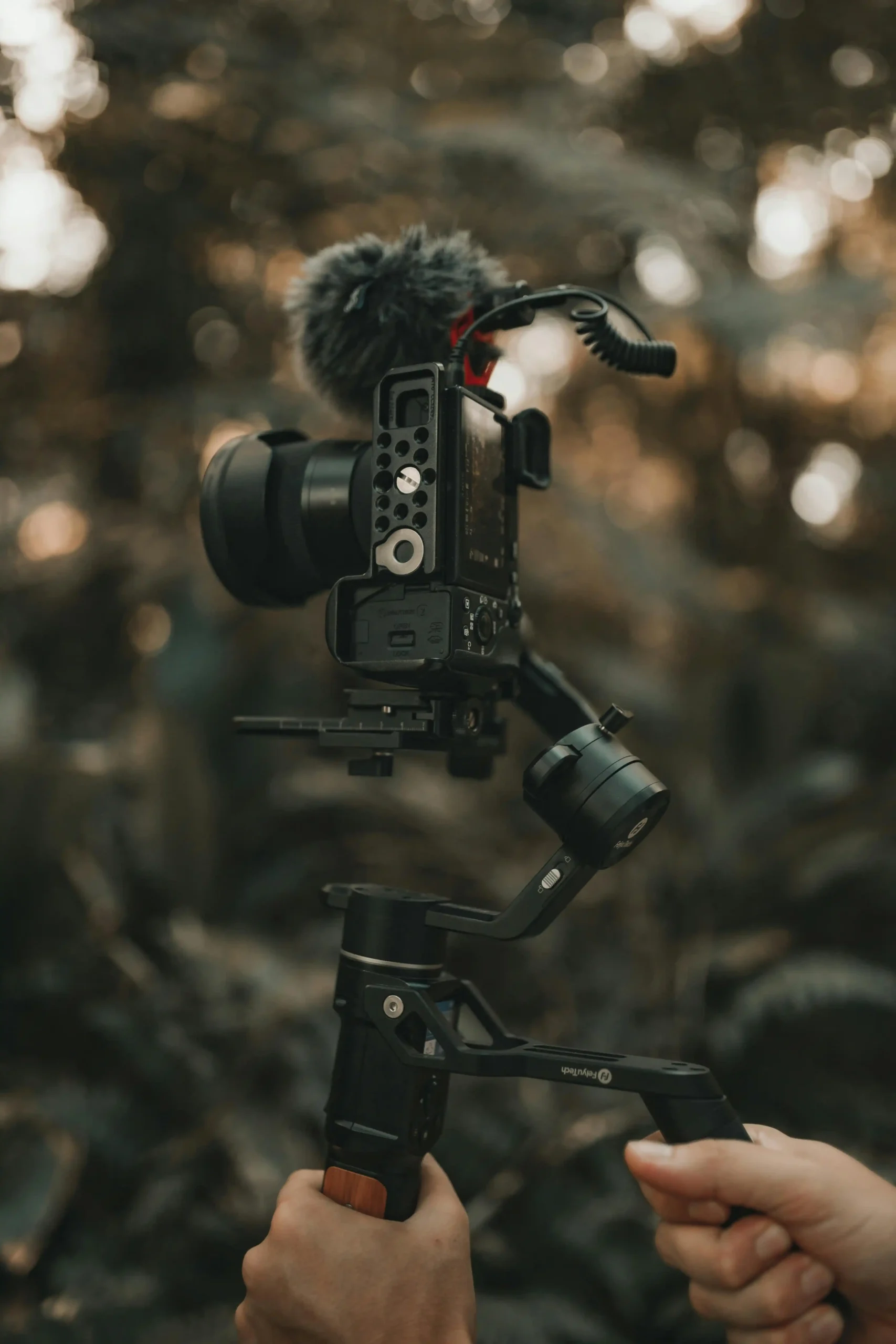 A handheld stabilized camera rig with a microphone, set up for filming in an outdoor environment.